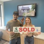 A couple holding a sold sign
