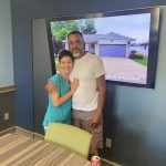 A couple posing in front of a picture of their new home